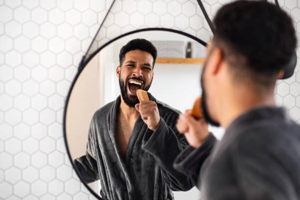 Young man having fun indoors at home, morning or evening routine concept. A young man having fun indoors at home, morning or evening routine concept. bathroom singing stock pictures, royalty-free photos & images