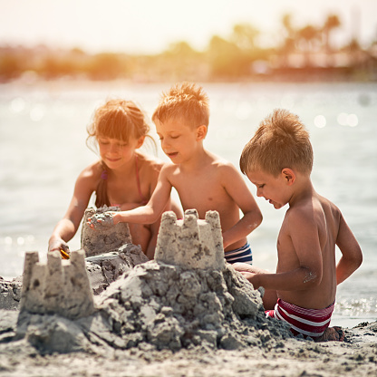 kids-building-a-sandcastle-on-beautiful-beach-picture-id540565392