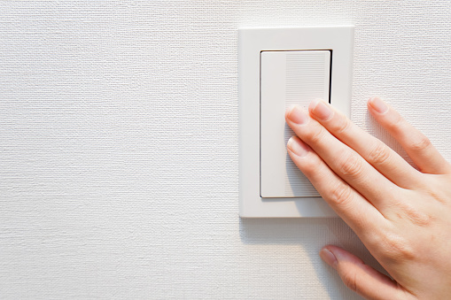 Unrecognizable person turning lights off with her finger on a light switch