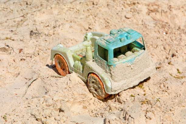 istock Abandoned old dirty children's toy car in sand.Selective focus 1000023344