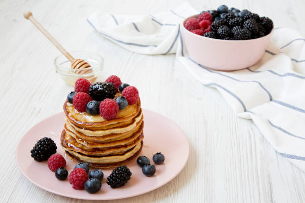 Pancakes with berries and honey, side view.