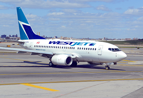 WestJet plane at airport, a Canadian low cost airline airliner illustrates the global trend of lower budget airlines aiming to take market share away from larger peers