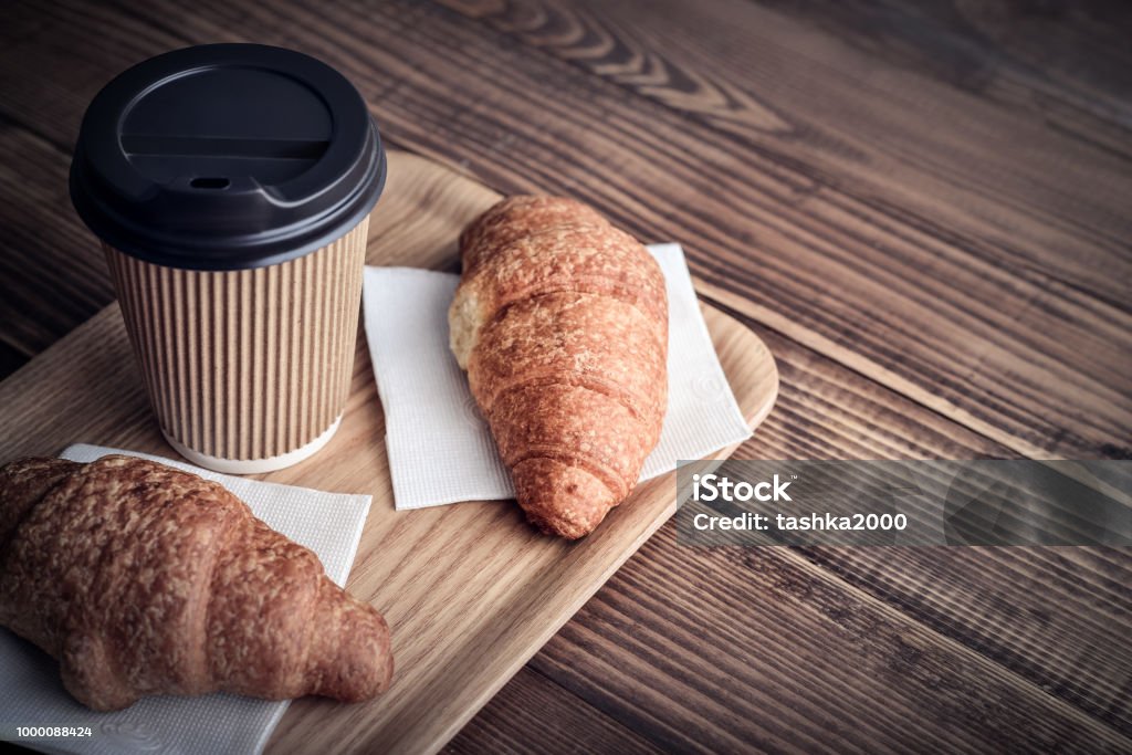 Two croissants and coffee-to-go Two croissants and coffee-to-go on tray over wooden background Coffee - Drink Stock Photo