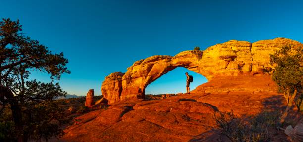 Hiker resting in Turret Arch A hiker watching sunrise in Turret Arch, Arches National Park, Utah natural bridges national park photos stock pictures, royalty-free photos & images