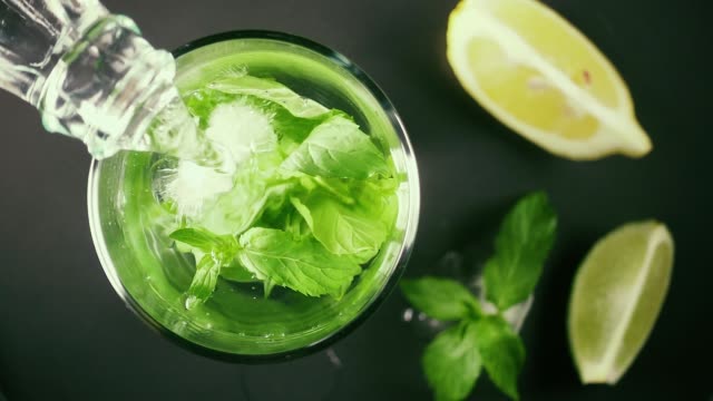 Slow motion in a glass with ice and mint pour water