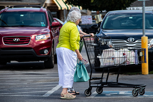Tulsa OK USA 6 2 2018 Little old ladies in the supermarket parking lot with a shopping cart and a musician playing for tips in the background