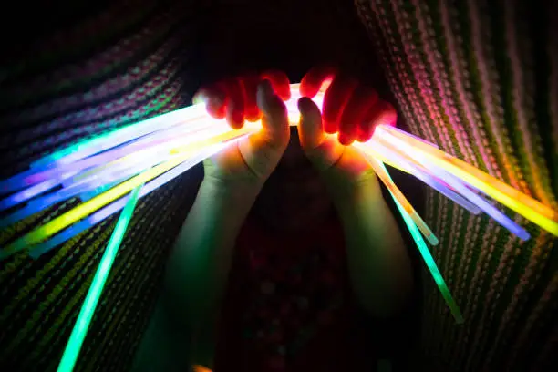 A cute little girl playing with glowsticks in her room