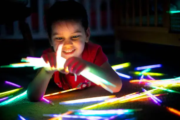 A cute little girl playing with glowsticks in her room