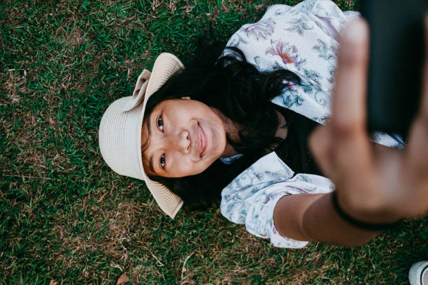 istock A beautiful woman taking selfie while lying down on grass 1000142144