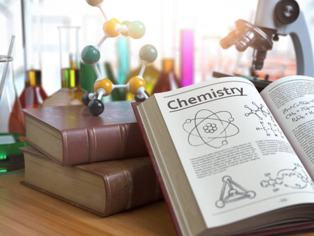 Chemistry education concept. Open books with text chemistry and formulas and textbooks, flasks with liquids and microscope in a classroom or a laboratory.