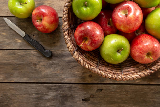 istock Fresh apples on rustic wood table with basket 1000164118