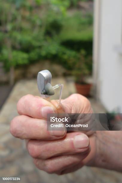 Closeup Hand Man Holding Hearing Aid On Blurred Background Stock Photo - Download Image Now