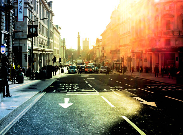 People walking along Regent Street St James’s in central London as vehicles wait for the traffic lights to change on a bright winter’s day. In the distance is the Victoria Tower of the Houses of Parliament and the Duke of York Column. (Colour manipulation.)