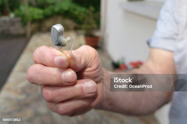 Closeup Of Senior Man Hand Holding Hearing Aid Stock Photo - Download Image Now - AIDS, Adult, Adults Only