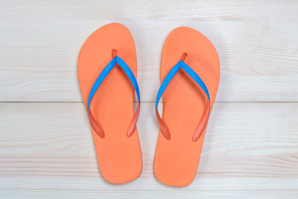 istock Orange flip flops isolated on wooden background. Top view 1000280158