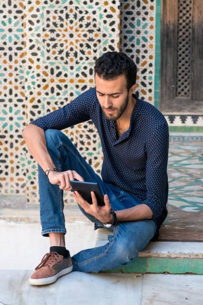 istock Handsome Muslim man working on tablet sitting on the floor 1000285810