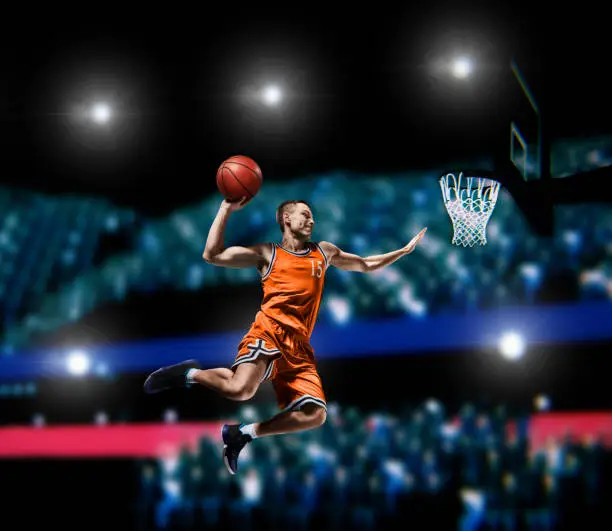 basketball player making slam dunk on basketball arena lights background