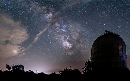 Domes of small telescopes in an observatory in the background of the milky way