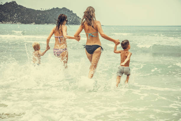 istock Friends playing in waves on beach 1000406620