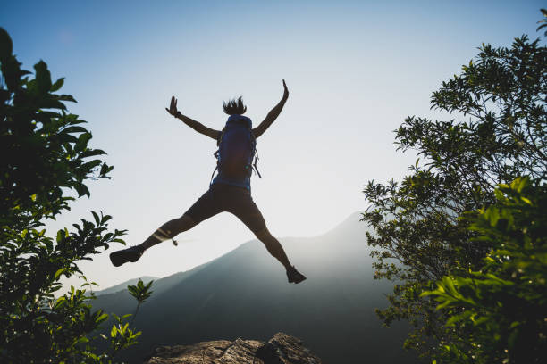 istock successful hiker jumping on summer sunrise mountain top cliff edge 1000459632