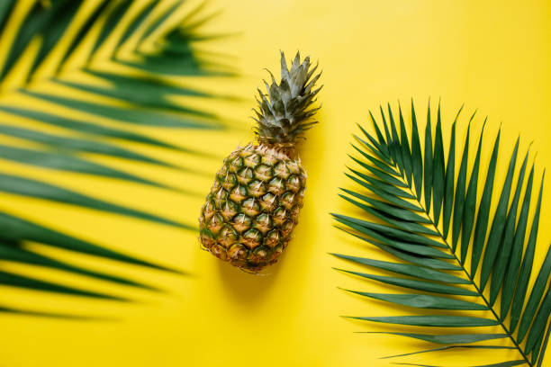 istock Ripe pineapple on vivid yellow background 1000476202