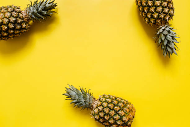 istock Ripe pineapple on vivid yellow background 1000476310