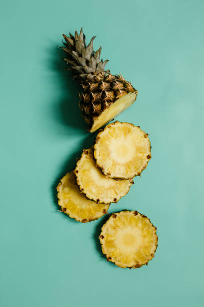 istock Sliced ripe pineapple on cyan blue, turquoise plain background. 1000476346
