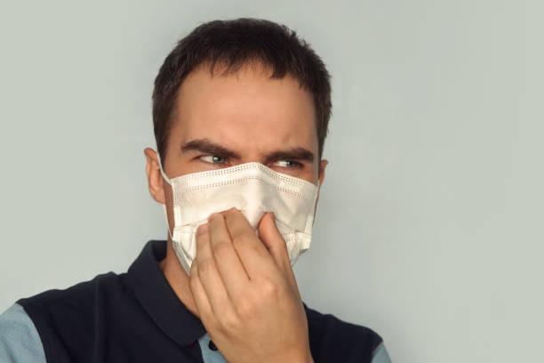 jovem pai segurando fralda suja suja os dedos de uma mão com máscara de gás sobre fundo branco. fedor de cheiro desagradável. poluição de gases ecologia ruim - facial expression unpleasant smell shirt caucasian - fotografias e filmes do acervo