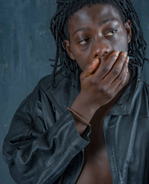 istock Young African man from Sierra Leone hand over mouth looking sideways. 1000488768