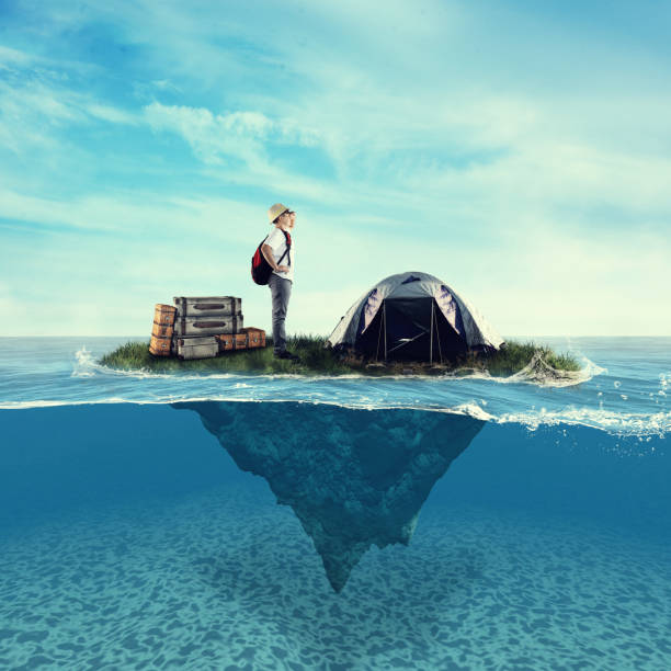istock Young explorer on a piece of land floating in ocean.Half underwater split. 1000564758