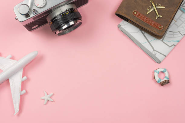 istock Retro camera with toy plane and passport on pastel pink background 1000580566