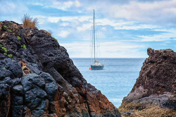 istock Blue yacht near rocky coastline 1000593246