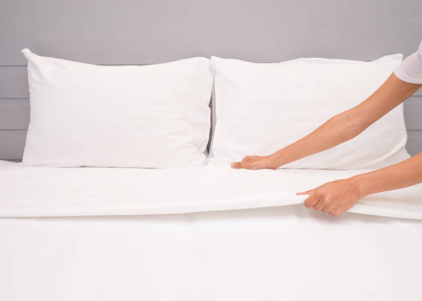 istock Close up hand set up white bed sheet in hotel room, Selective focus 1000680972