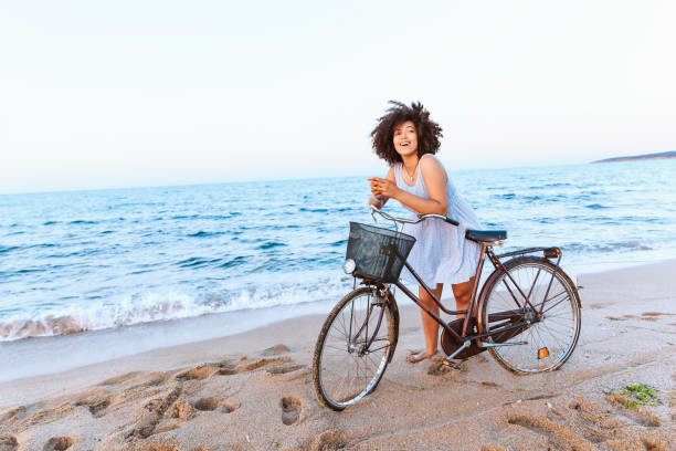 istock African woman biking and social networking on beach 1000685396