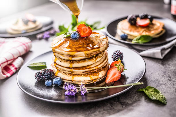 istock Pancakes with strawberries blackberries blueberries lavender mint leaves and maple syrup. 1000694340