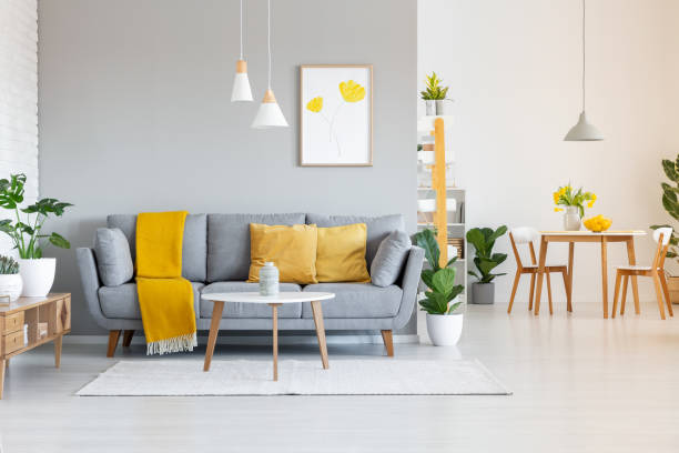 pomarańczowy koc na szarej sofie w nowoczesnym wnętrzu mieszkania z plakatem i drewnianym stołem. prawdziwe zdjęcie - cushion sofa pillow indoors zdjęcia i obrazy z banku zdjęć