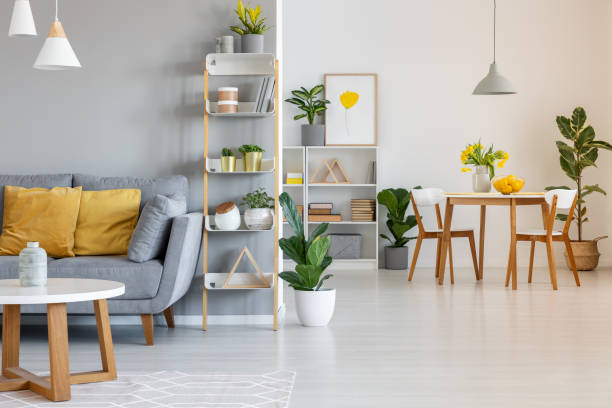 istock Orange pillows on grey settee in spacious flat interior with chairs at wooden table. Real photo 1000701178