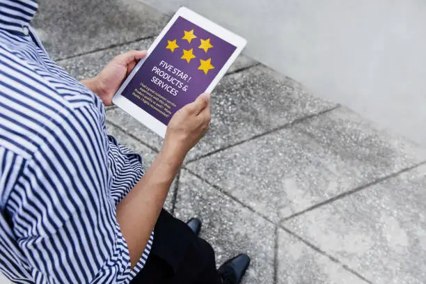 Photo of Customer Experience Concept. Man standing outside and Reading Positive Online Review via Tablet before Buying Products. Top view