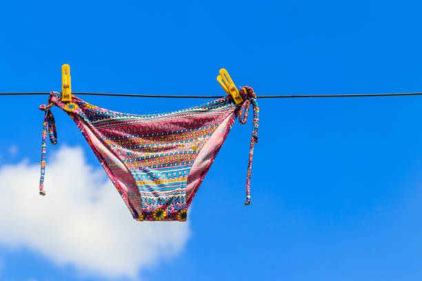 istock Drying female swimsuit hanging on a rope against blue sky 1000715584