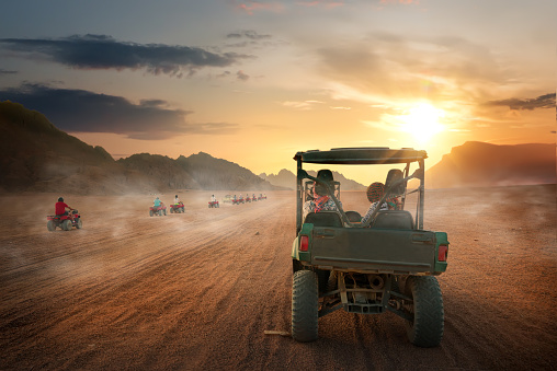 Carefree couple having fun while driving quad bike in the desert. Copy space.