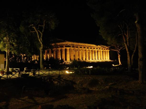 Paestum - Temple of Neptune at night Paestum, Salerno, Campania, Italy - July 1, 2018: Temple of Neptune illuminated in the Archaeological Park of Paestum temple of neptune doric campania italy stock pictures, royalty-free photos & images