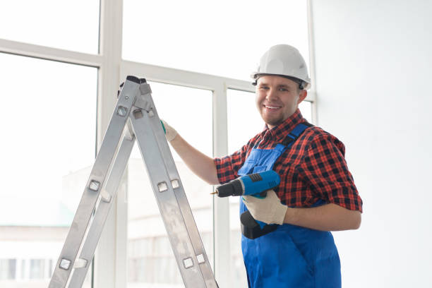 istock Happy male builder standing on ladder with drill infront of window 1000730972