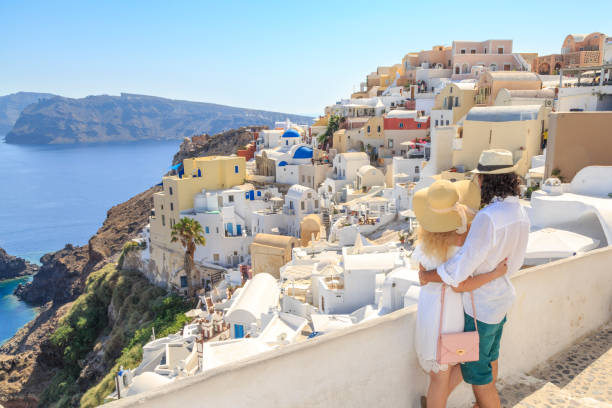 Couple watching the view of cityscape of Oia village in Santorini island, Greece Couple watching the view of cityscape of Oia village in Santorini island, Greece happy couple on vacation in santorini greece stock pictures, royalty-free photos & images