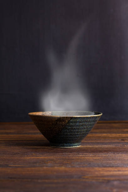 Ceramic bowl with smoke on wooden table.