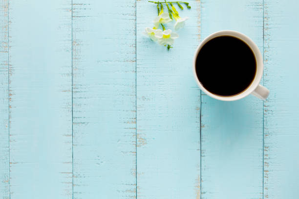 istock White coffee cup with black coffee and flowers on wooden table. 1000732004