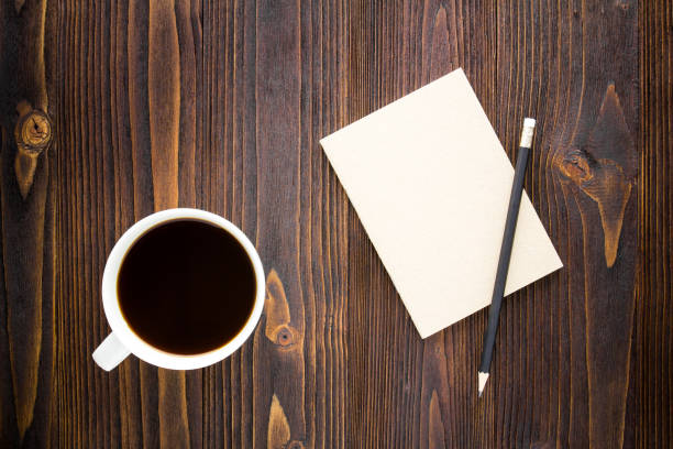 istock White coffee cup with black coffee ,notebook and pencil on wooden table. 1000732060