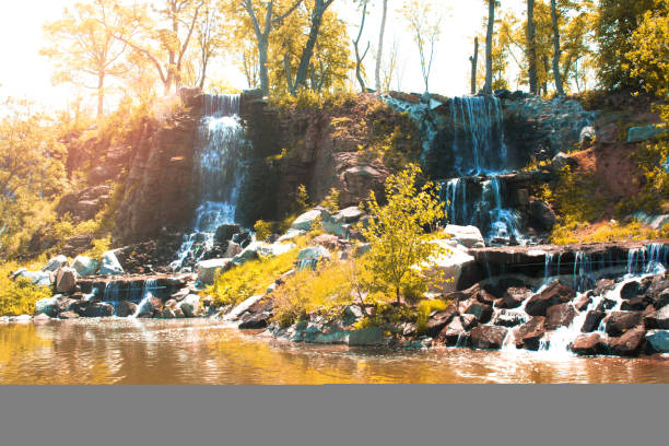 istock beautiful waterfall under sunlight, many beautiful water jets surrounded by green forests. 1000751450