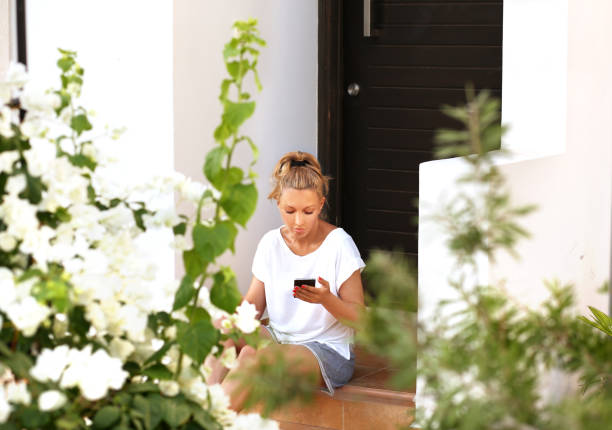 istock Woman using smart phone sitting on the steps 1000755768