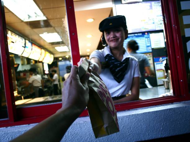 A fast food chain worker gives a customer a purchased product at a drive thru. stock photo