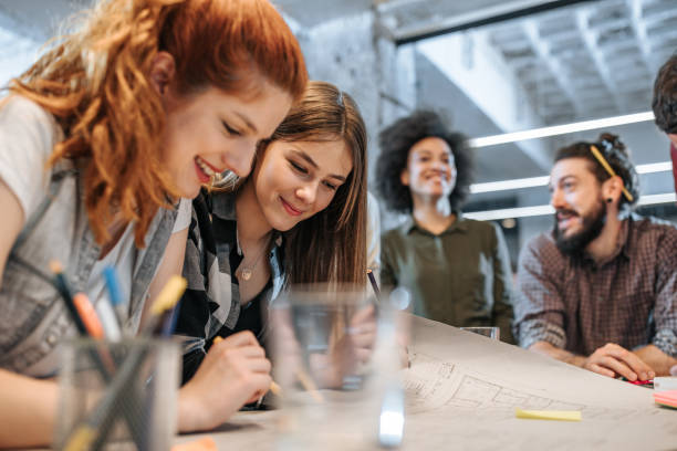 istock Happy female architects cooperating while examining blueprints in the office. 1000834290